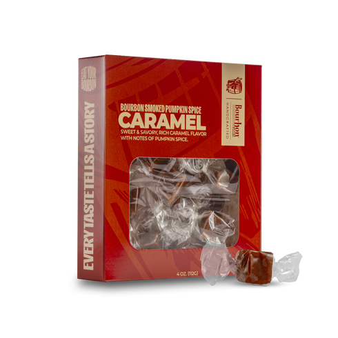 A red box of Baum Koen Bourbon Smoked Pumpkin Spice Caramel candies with a clear window showing the wrapped candies inside, plus two unwrapped caramel pieces in clear wrapping placed in front on a white background.