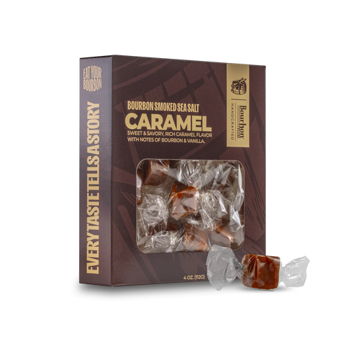 A box of Bourbon Smoked Sea Salt Caramel candies with two individually wrapped caramels placed in front on a clean white background.