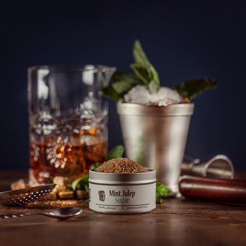 Beautiful lifestyle of a mint julep the iconic Kentucky Derby cocktail made special with bourbon barrel foods, mint, julep sugar. All of the wonderful bartending tools seen in the background and bursting with fresh mint and mint julep sugar.