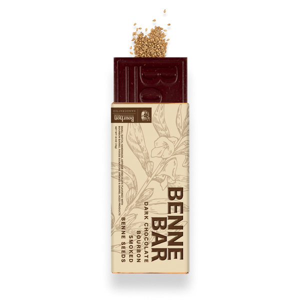 A Bennea dark chocolate bar with embedded seeds, shown with its beige paper wrapper and a small pile of seeds on top, isolated on a white background.
