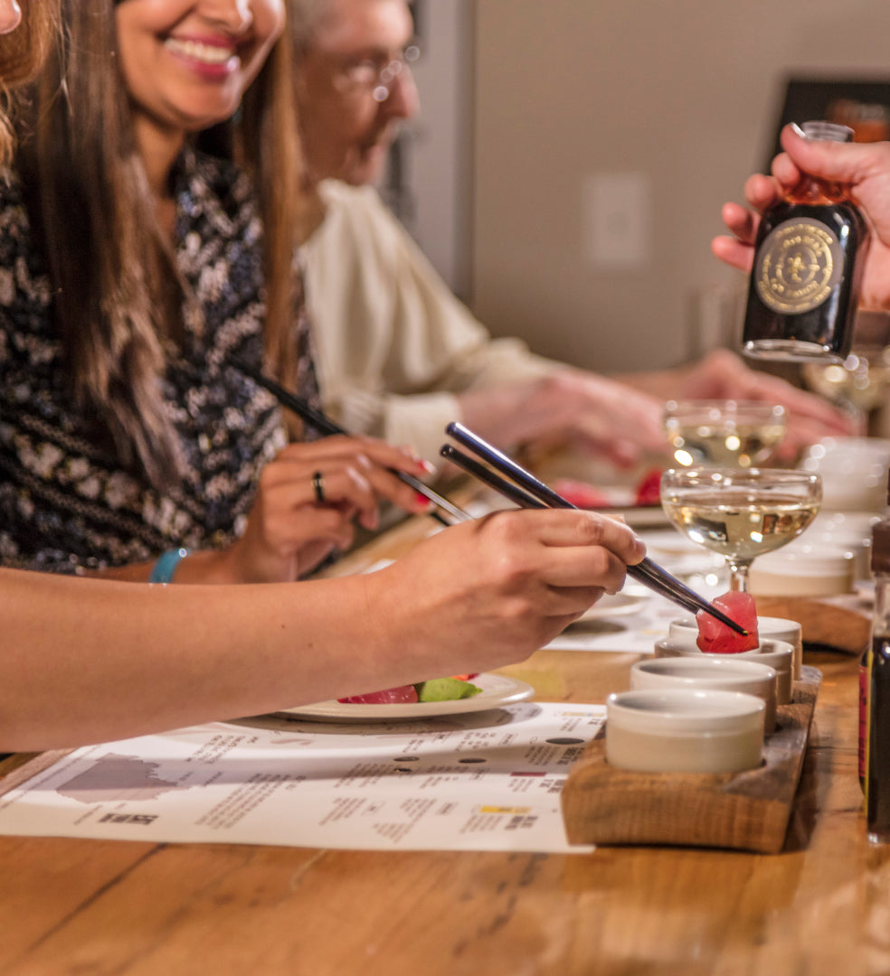 Smiling people tasting Bourbon Barrel Foods Soy Sauces after a tour
