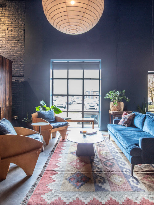 A well-lit lounge space with a sofa, coffee table, and chairs at Bourbon Barrel Foods retail space