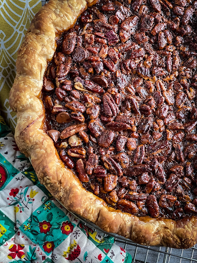 A freshly baked pecan pie with a golden, flaky crust and a rich, caramelized pecan topping, resting on a cooling rack.