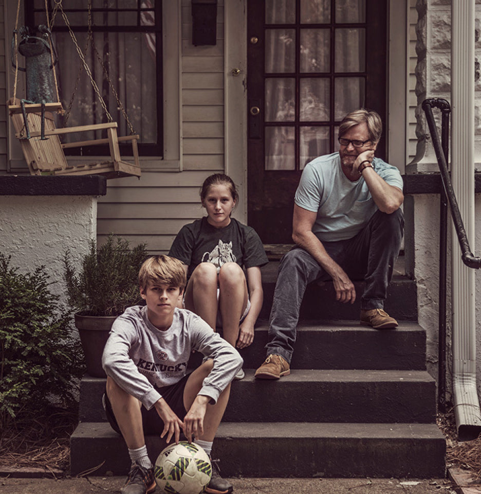 Matt Jamie and his children sitting on the front steps of a house . 