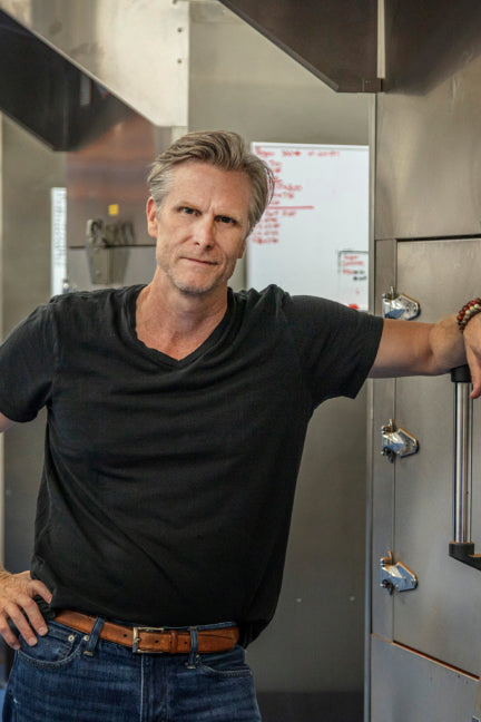 Matt Jamie leaning against an industrial smoker used to smoke spices