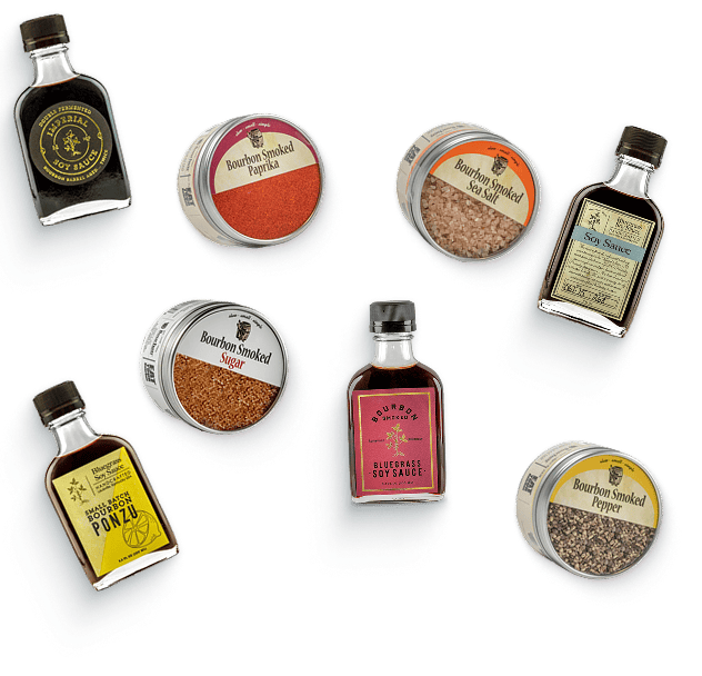 Tour and Taste Louisville Bundle: Bluegrass, Bourbon Smoked and Imperial Double Fermented soy sauces, Small Batch Bourbon Ponzu, and tins of bourbon smoked pepper, sea salt, paprika and sugar, scattered on a steel-blue background