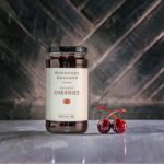 Woodford Reserve Bourbon Cherries with a marble background and two plump and delicious bourbon cherries.