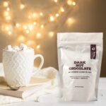 Bourbon Barrel Foods Dark Hot Chocolate with Bourbon Smoked Sea Salt with twinkle lights and a cozy blanket with a ready to sip serving filled to the rim with marshmallows.