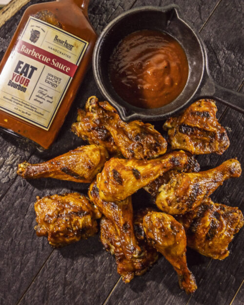 Bourbon Barrel Foods Barbecue sauce in bottle and a bowl with some chicken wings