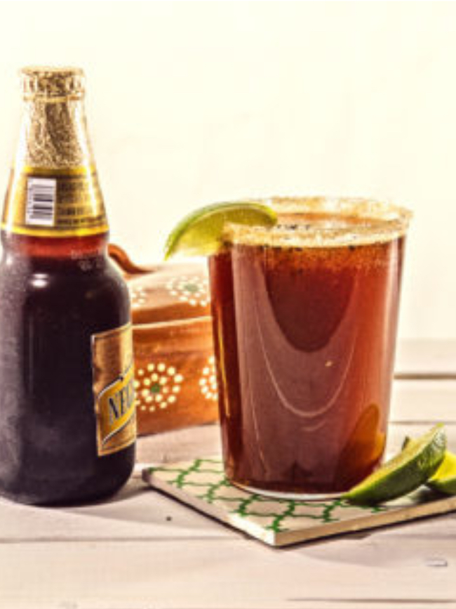 Photo of a michelada next to a bottle of beer