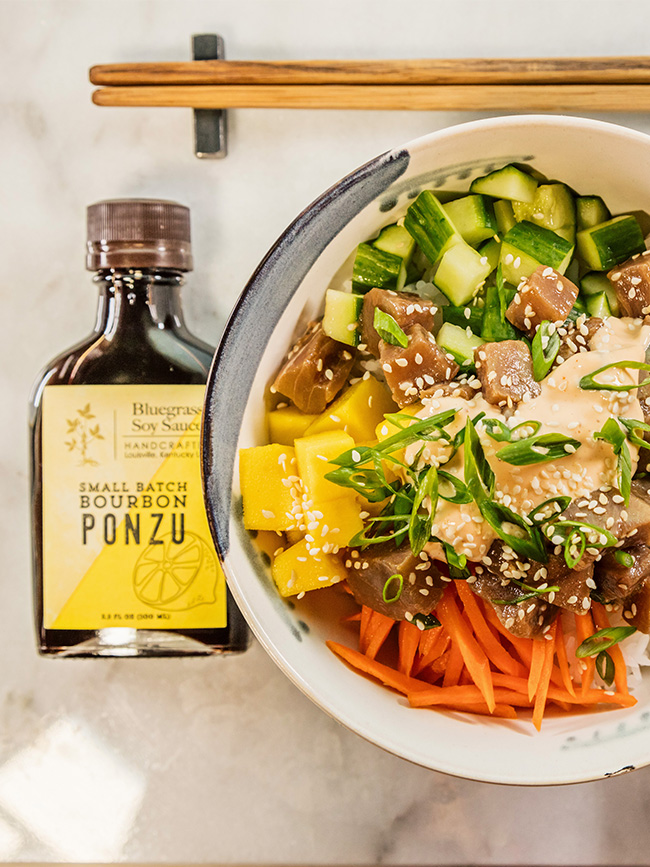 Overhead photo of a poke bowl next to bottle of ponzu