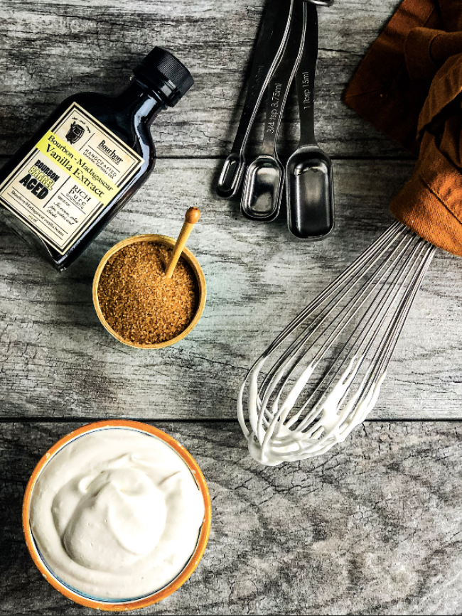 Overhead photo of bourbon Barrel Whipped cream below a whisk Bourbon Barrel foods vanilla extract and sugar