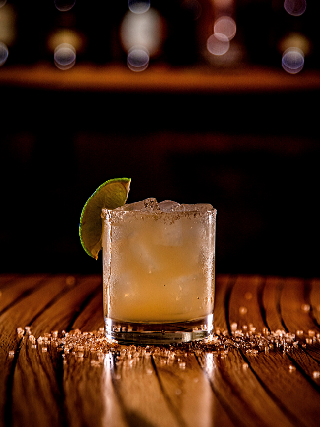 Smoked soy margarita in a clear glass with a lime
