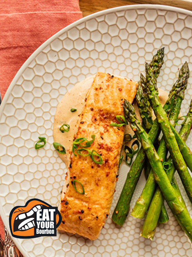 an overhead photo of Salmon next to asparagus with the Eat your bourbon logo in the corner