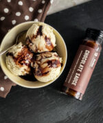 Bourbon Barrel Foods Chocolate Sauce with Cacao Nibs next to a bowl of ice cream