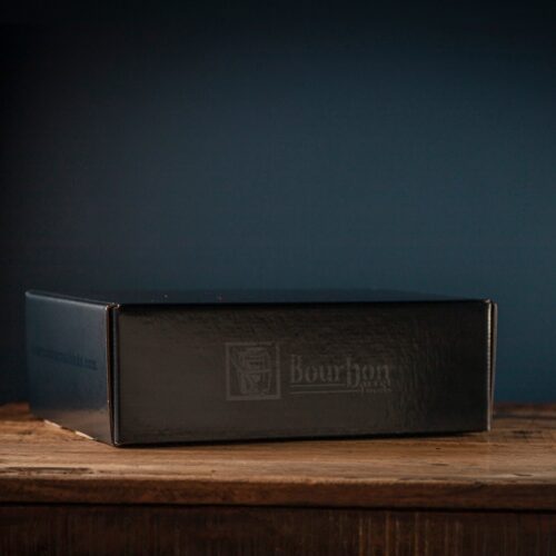 Bourbon Barrel Foods Branded Gift Box closed on a table with a blue background.